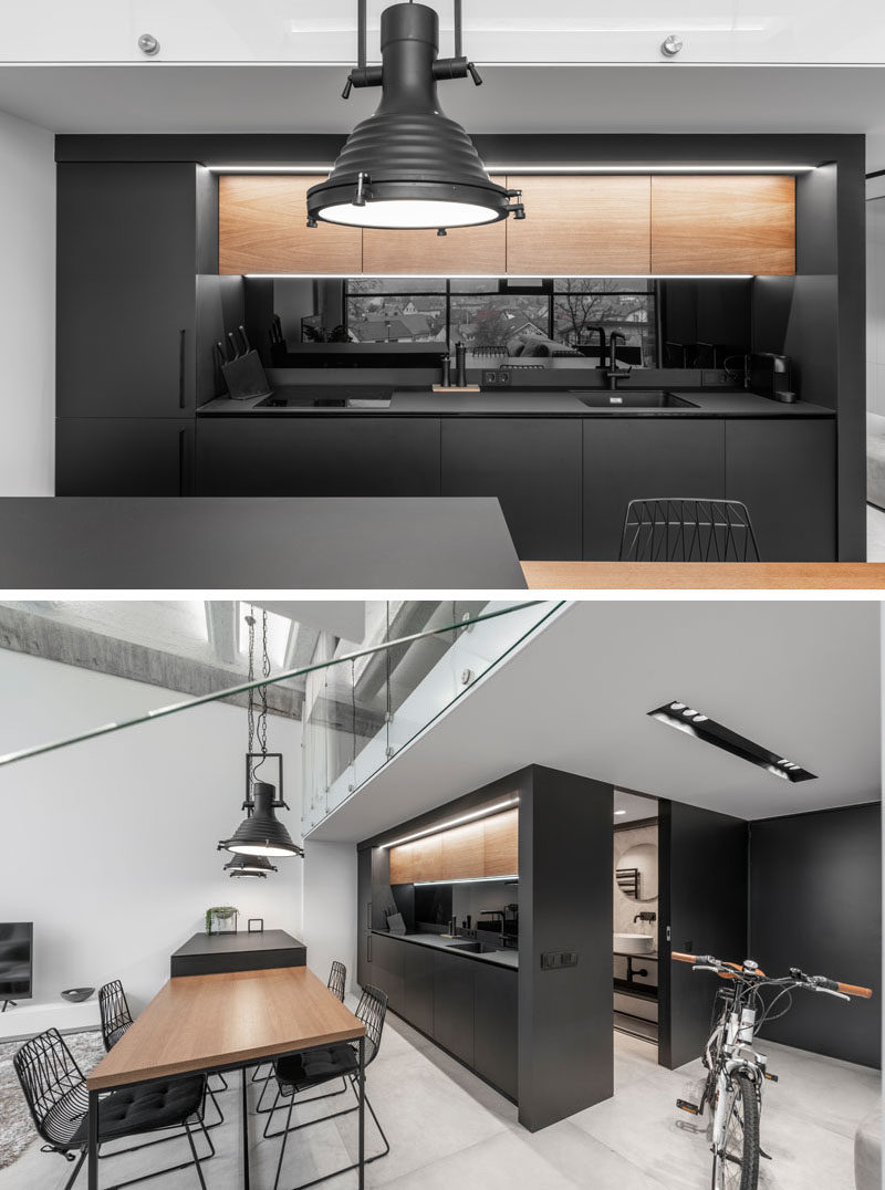 In this modern kitchen, the upper wood cabinetry complements the dining table, contrasts the black cabinets, and adds a natural touch to the minimalist interior. #ModernKitchen #BlackKitchen