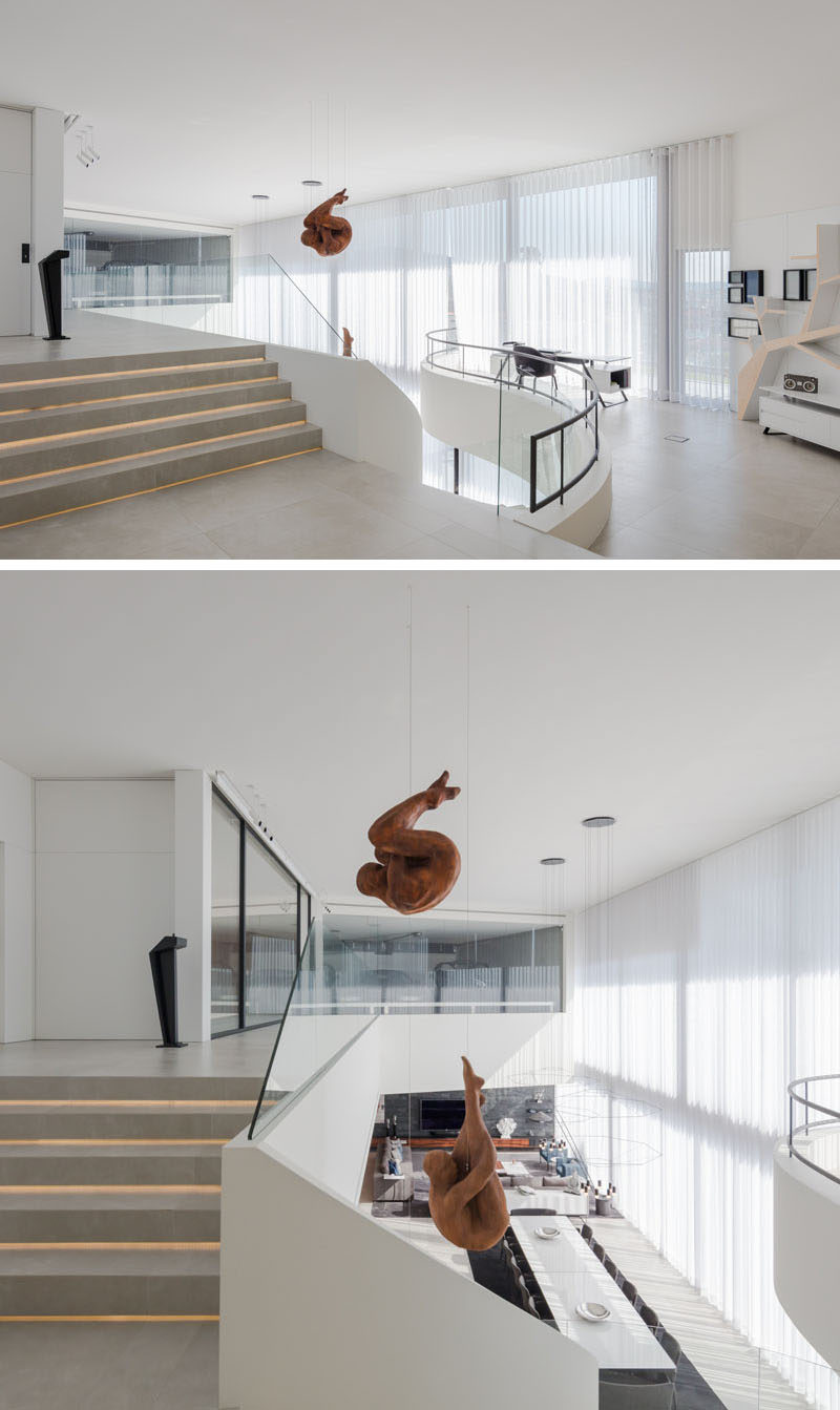 At the top of this modern curved staircase, there's a small area set up as a home office, that overlooks the sculptures and the dining area below. #HomeOffice #HangingSculptures