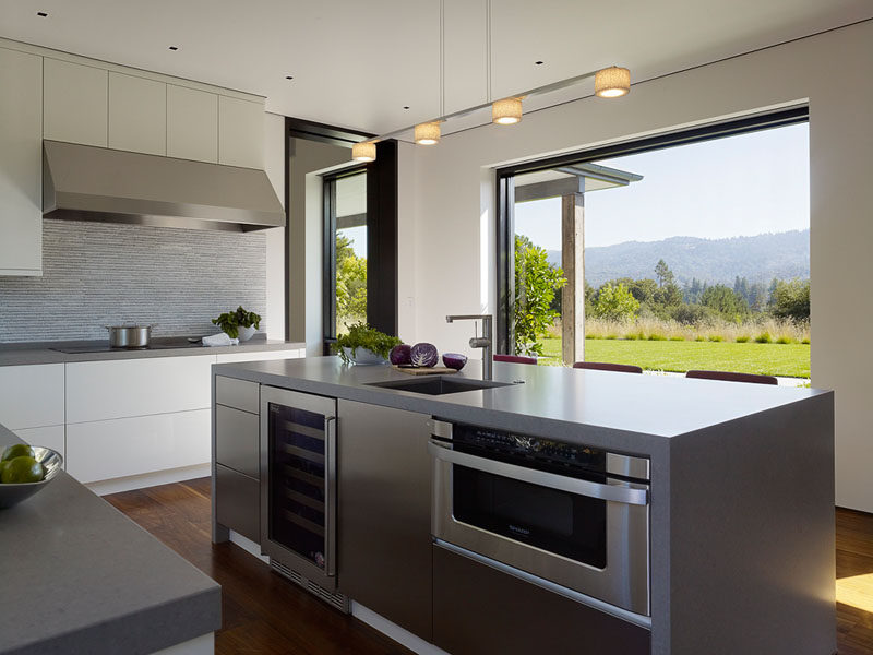 The large window in this modern kitchen perfectly frame the view of the garden and hills in the distance. #ModernKitchen #KitchenDesign #Windows