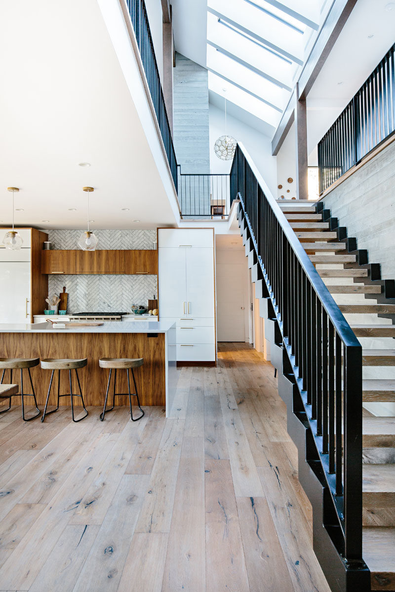 In this modern lake house, a tiled backsplash in a herringbone pattern adds a decorative touch to the kitchen, while wood and steel stairs lead to the upper floor of the home. #InteriorDesign #Kitchen #Stairs