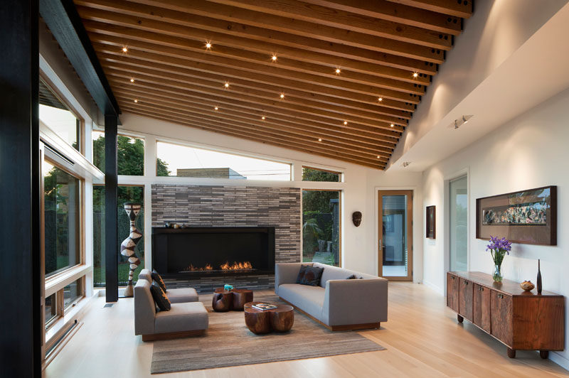 This modern living area is enclosed by a continuous glass wall, protected by a 6-ft roof overhang. #LivingRoom #Fireplace