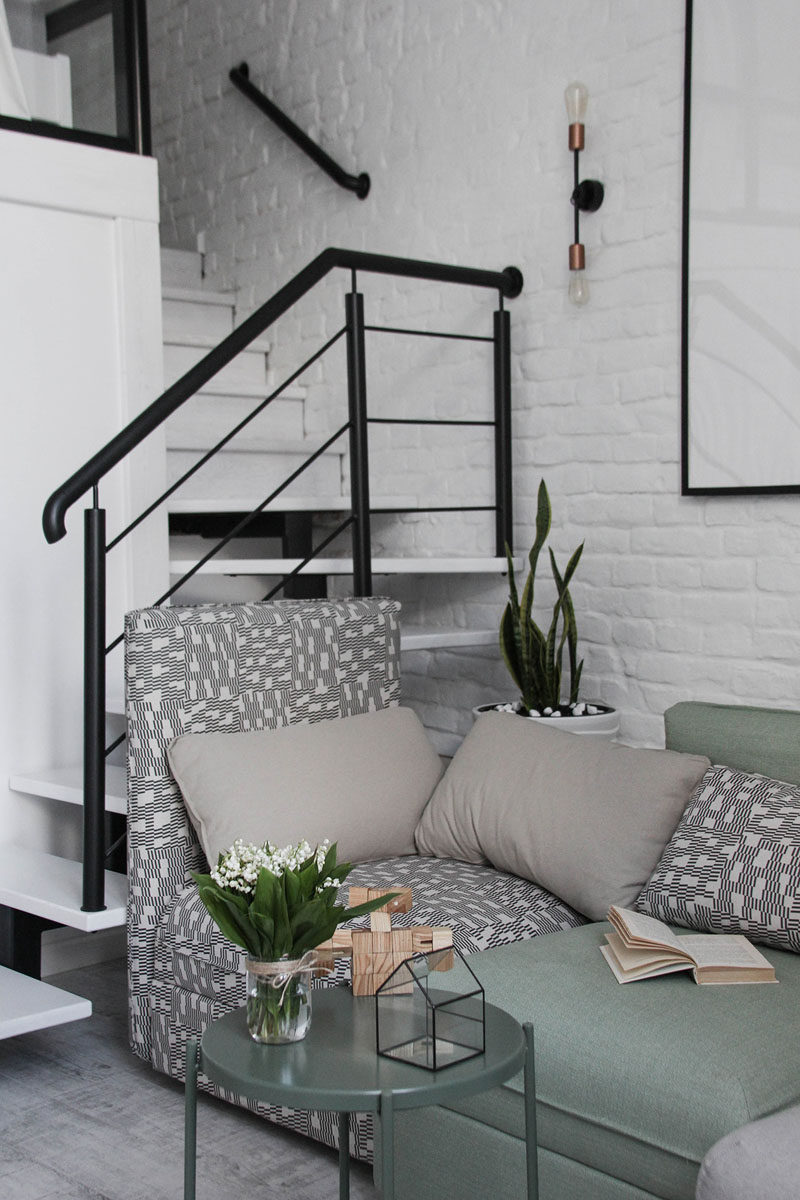 Black steel stairs with white treads lead up to the mezzanine level of this modern loft apartment. #Stairs #Staircase #StairDesign