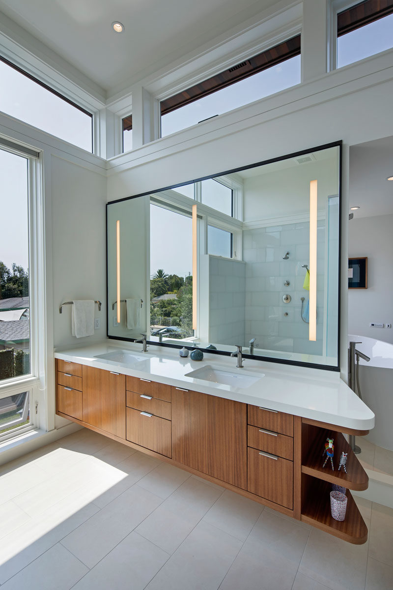 In this modern master bathroom, high operating clerestory windows are used to reduce heat gain in summer months, while a large mirror helps to reflect light throughout the interior. #ModernBathroom #BathroomDeisgn
