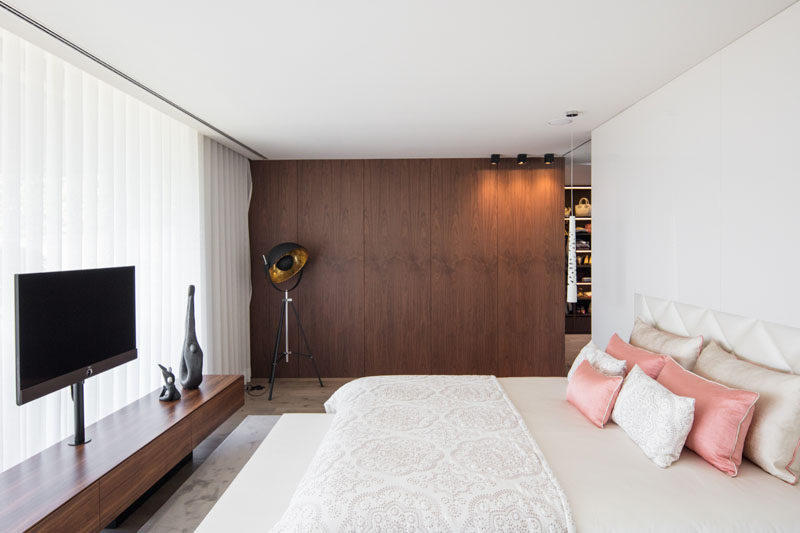 In this modern master bedroom, a wood accent wall adds a natural touch to the mostly white room. #MasterBedroom #WoodAccentWall