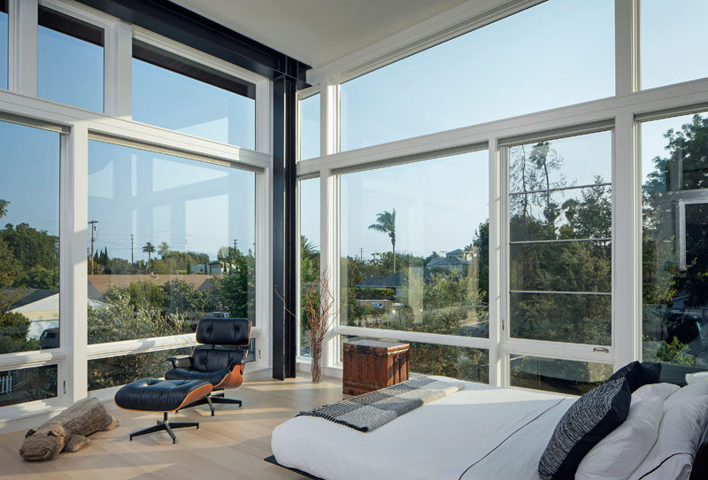 This modern master bedroom has walls of windows that fill the room with natural light and provide a view of the neighborhood. #MasterBedroom #Windows
