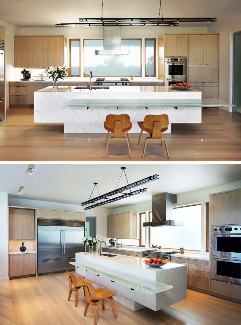 This modern kitchen features both wood cabinetry and a sculptural quartz kitchen island with a cast-glass breakfast counter. Hanging above the island is a delicate custom steel light fixture designed by FINNE. #KitchenDesign #KitchenIsland #ModernKitchen