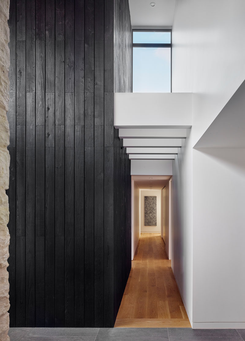 Inside this modern home, a double-height vaulted entryway with a shou sugi ban accent, welcomes guests and guides them to the various areas of the house. #ShouSugiBan #Hallway