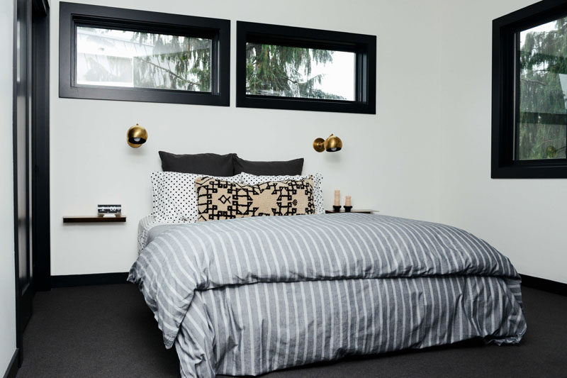 In this contemporary bedroom, simple floating shelves and single sconces have been placed on either side of the bed, while dark flooring contrasts the white walls. #Bedroom #ModernBedroom