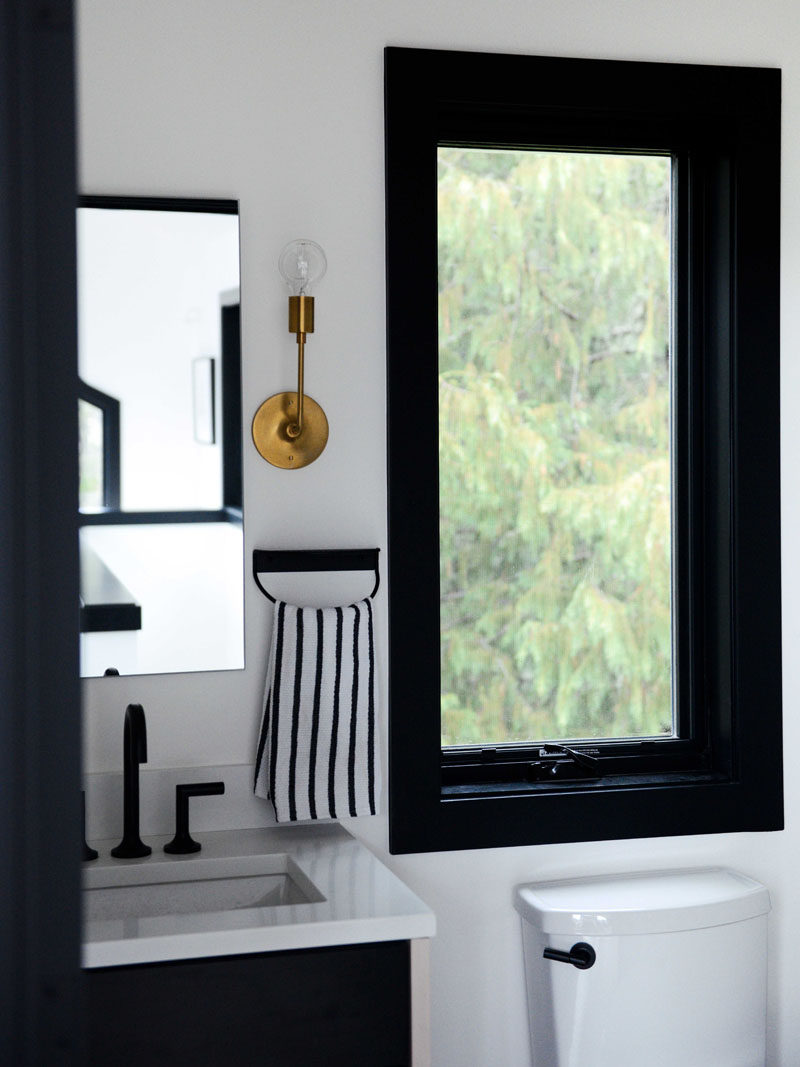 The black and white theme continues in the bathroom, with a brass light fixture adding a metallic accent. #Bathroom #BlackAndWhiteBathroom