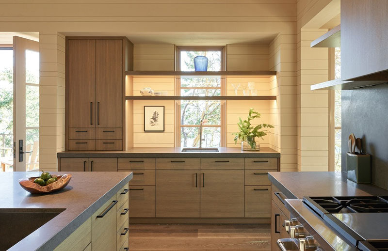 The contemporary kitchen in this guest house has a simple and natural color palette of light wood and grey countertops. #KitchenDesign #WoodKitchen #GreyCountertops