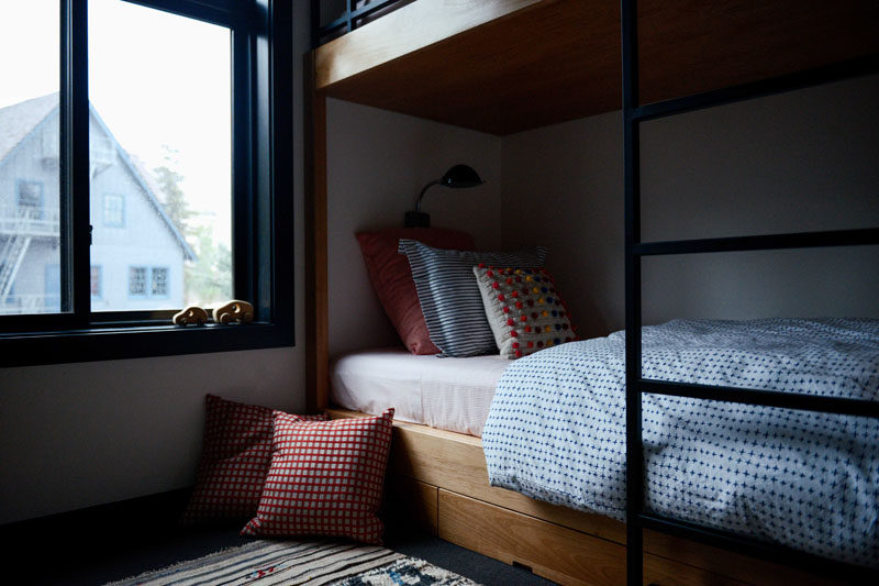 In this modern kids room, there's a set of wood bunk beds with a minimalist black ladder. #BunkBeds #KidsRoom #Bedroom