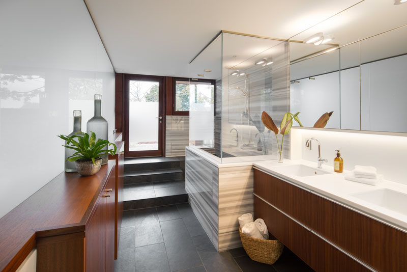 In this modern bathroom, wood cabinetry adds a natural touch, while a partially frosted door provides access to the outdoors. #BathroomDesign #ModernBathroom