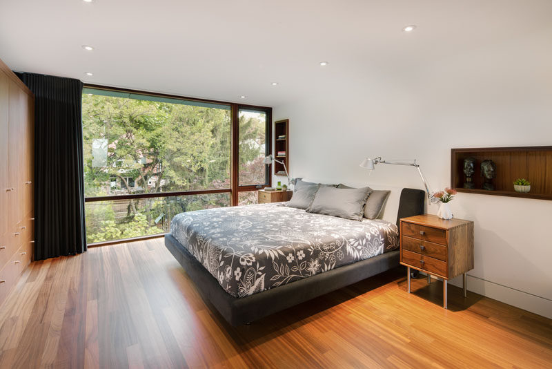 In this modern bedroom, wood-lined shelving has been built into the wall, while opposite the bed is a wall full of cabinetry. #Bedroom #Shelving