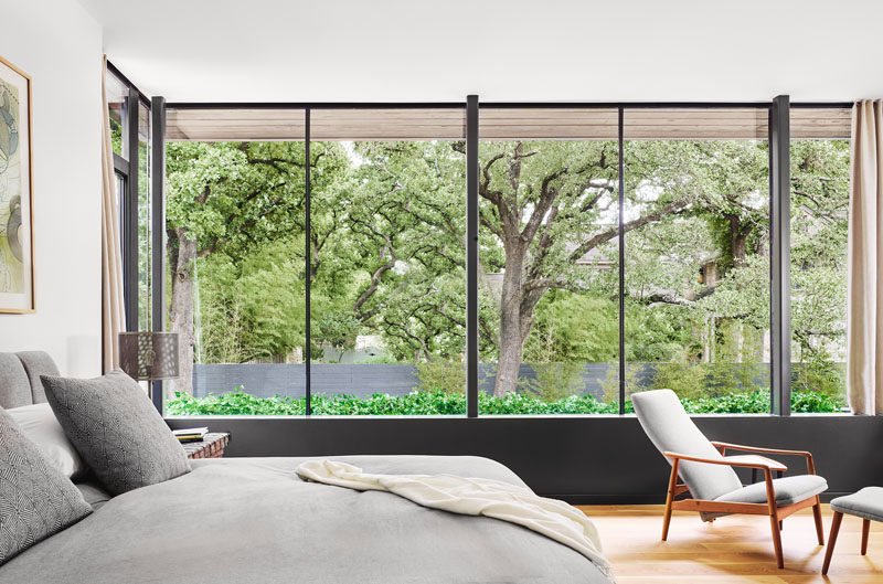 This modern bedroom features a wall of windows that overlook the trees outside. #Bedroom #Windows