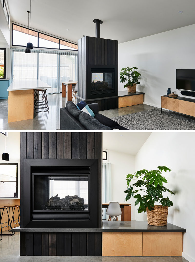 The main social areas of this modern house are open plan, with the living room enjoying one side of the double-sided fireplace, that features a black stained timber boards. #ModernFireplace #BlackStainedWood #FireplaceDesign #DoubleSidedFireplace