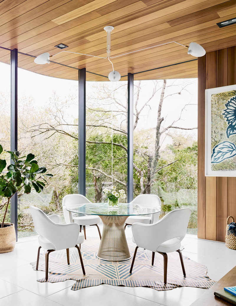 Floor to ceiling windows provide an abundance of natural light in this dining room, while a simple white light is positioned above the dining table, anchoring it in the open area. #DiningRoom #Windows