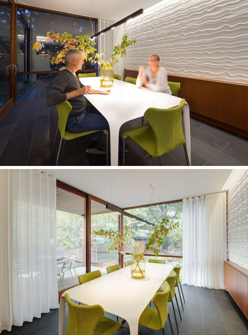 This modern dining room has a textured wall, and floor-to-ceiling windows overlooking the backyard. #DiningRoom #ModernDiningRoom