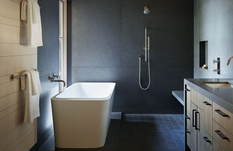 This modern master bathroom features grey walls, wood accents and a freestanding bathtub that takes advantage of the views fro the window. #Bathroom #ModernBathroom