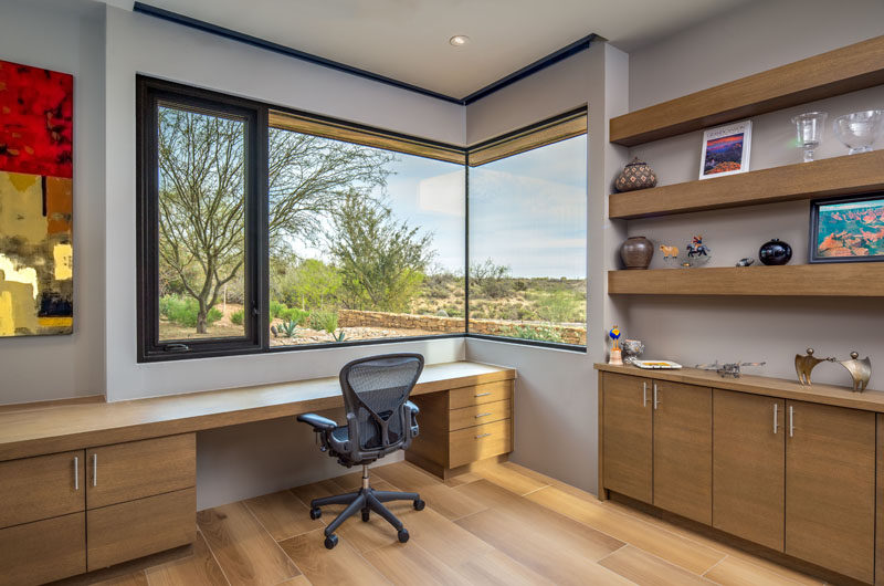 This modern home office has open shelving, wood cabinetry, and a window that wraps around the corner of the room. #HomeOffice #Window