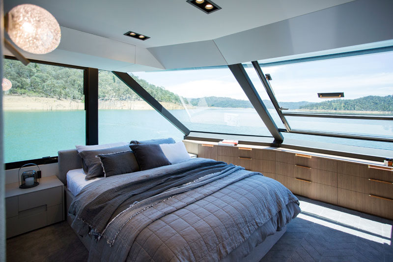 The master bedroom of this modern houseboat has wrap around windows, and plenty of built-in storage. #Bedroom #Houseboat