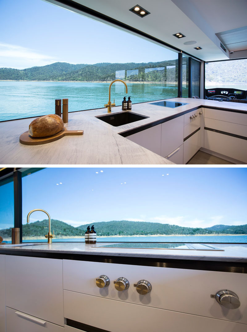 In the houseboat kitchen, a large picture window perfectly frames the views, while the cabinetry has a minimalist appearance. #Houseboat #ModernKitchen #PictureWindow