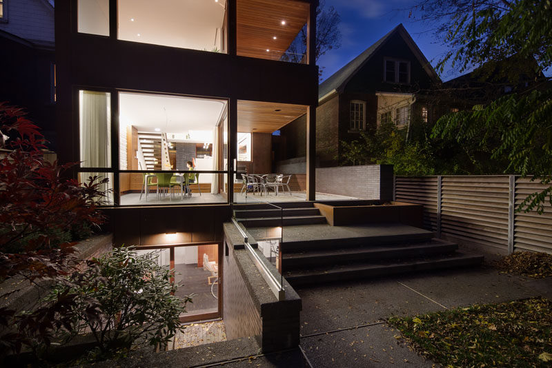 The dining room in this modern house provides access to the covered deck, which has steps that lead to the backyard. #ModernHouse #OutdoorDining