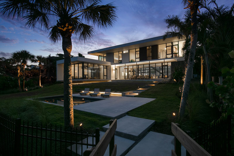 This modern house has steps that lead down to the swimming pool and deck. #ModernHouse #Landscaping #SwimmingPool