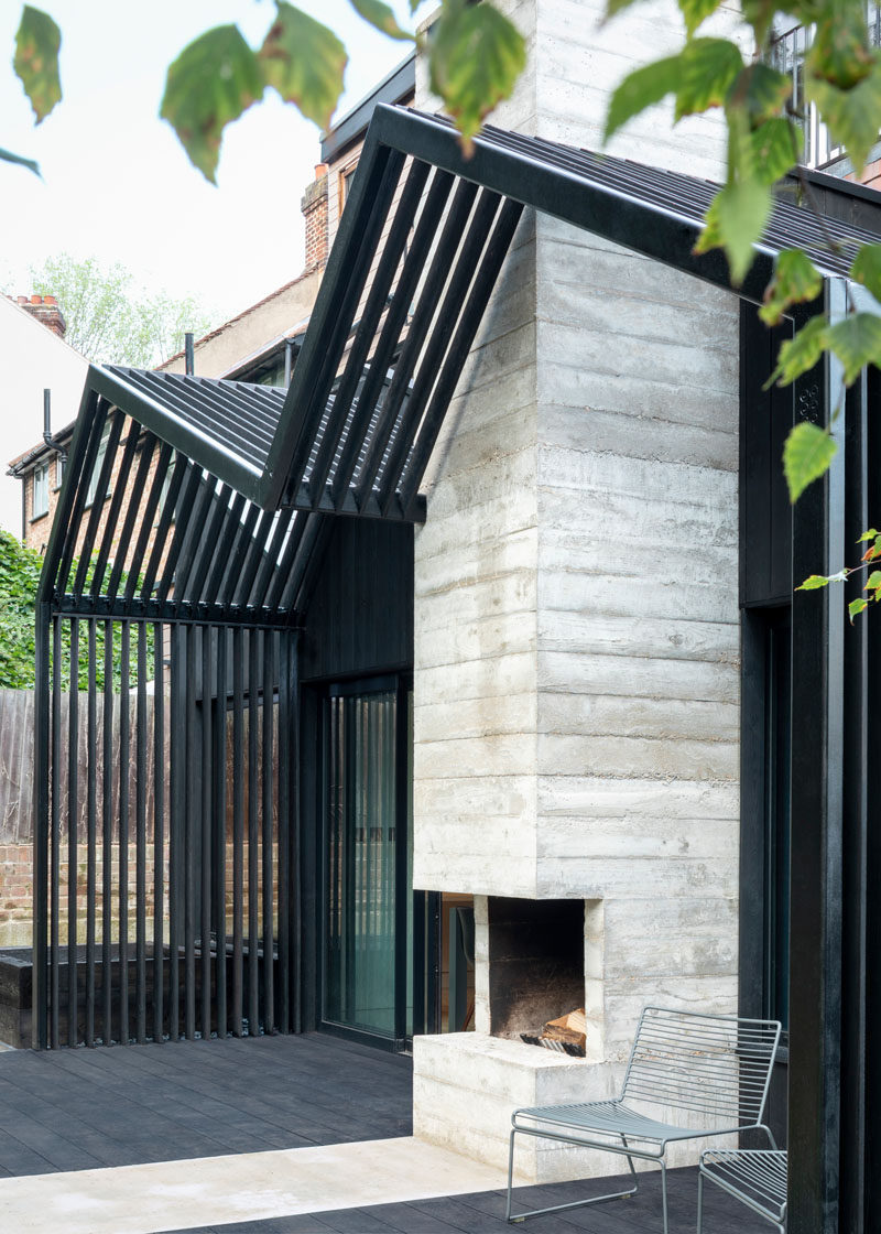 The dark exterior of this contemporary extension is contrasted by a ribbon of board-formed concrete that highlights the fireplace. #OutdoorFireplace #ExteriorFireplace