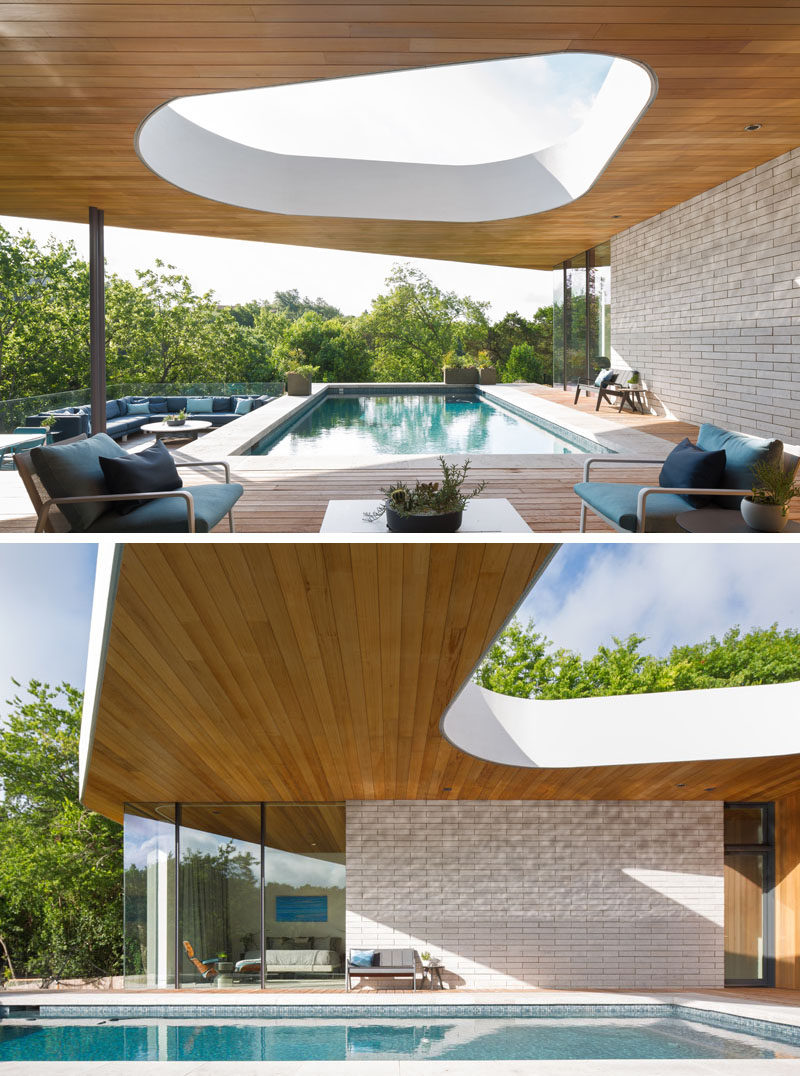 This modern house has a large outdoor area with a cut-out in the roof, a swimming pool and wood deck, and an outdoor lounge area. #SwimmingPool #Deck #OutdoorLounge