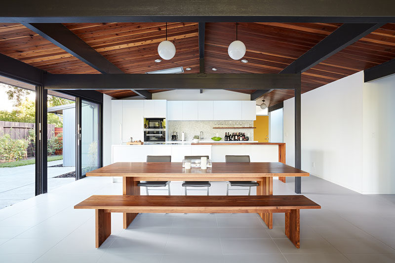 In this open plan dining room, a wood dining table complements the exposed stained wood ceiling above. #DiningTable #OpenPlanInterior #WoodCeiling