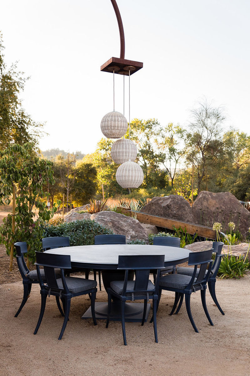 This alfresco dining area has three pendant lights hanging above a round dining table. #OutdoorDining #AlfrescoDining