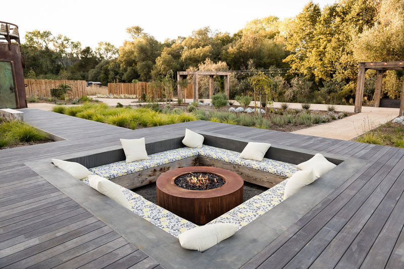 Central to this landscaped backyard is a wooden pathway that leads to a large sunken lounge with bench seating and a fire pit. #SunkenLounge #Landscaping #Firepit