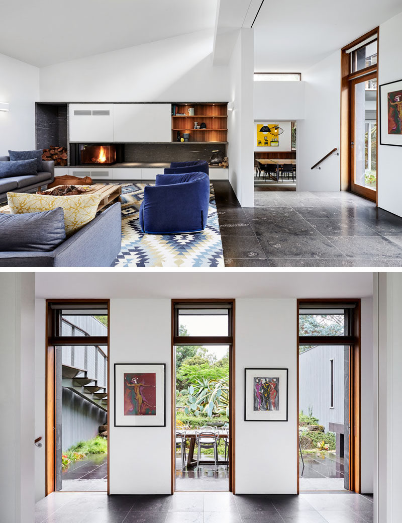 In this modern living room, there's a fireplace with built-in wood storage and wood bookshelves, while three doors adjacent to the sitting area, open up to the landscaped courtyard where there's an outdoor dining area. #ModernLivingRoom #LivingRoom #OutdoorDining