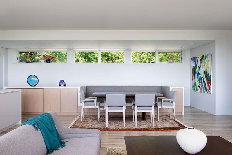 The dining area of this modern house has banquette seating that's been built into the sideboard design, while clerestory windows add a touch of natural light. #DiningRoom #BanquetteSeating #ModernInterior