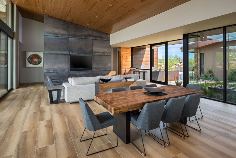 A sloped wood ceiling helps to keep the interior of this modern house feeling open and bright. #WoodCeiling #SteelAccentWall #DiningRoom