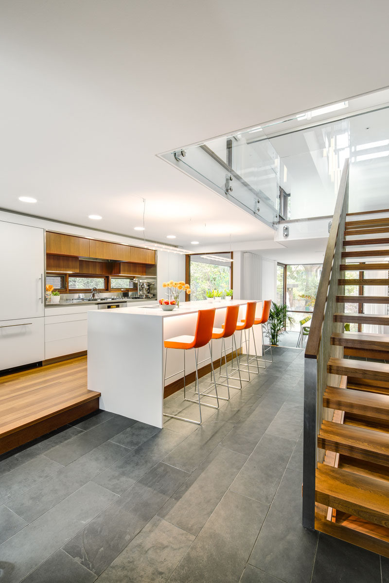 In this modern kitchen, wood cabinets contrast the surrounding white cabinetry, and a large island offers bar height seating. #Kitchen #ModernKitchen