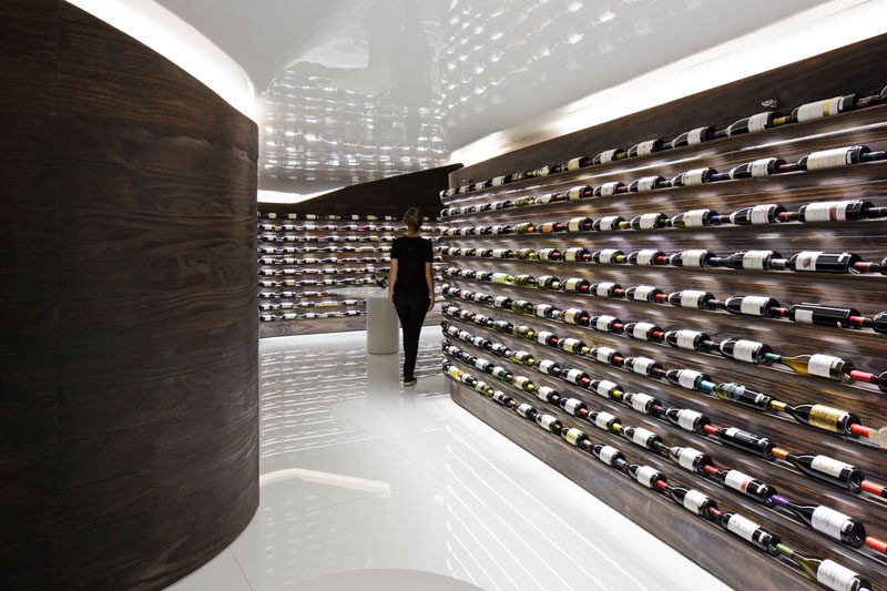 Studio Arthur Casas have designed a wine store and bar in Sao Paulo, Brazil, that features walls of dark wood that showcase the available wines. #WineStore #RetailDesign #WineBar #WineStorage