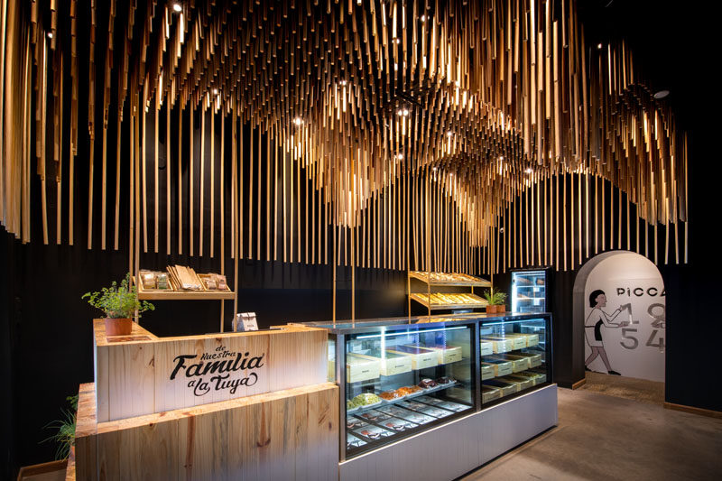 This modern retail store features 1954 broomsticks (commemorating the year of the founding of the family business), that were used to create a sculptural wood ceiling installation. #ModernRetailStore #StoreDesign #WoodCeiling