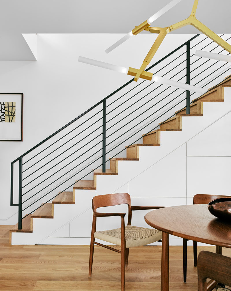 This modern house has a dining area with a round table and an artistic chandelier, that sit beside are the stairs. #Stairs #DiningRoom