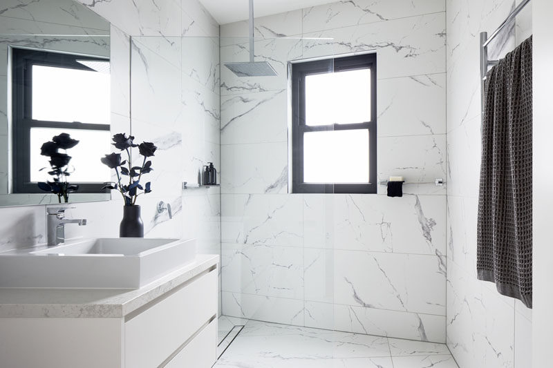 The frameless glass shower screen in this modern bathroom allows the natural light from the window to flow throughout the room. #BathroomDesign #WhiteBathroom