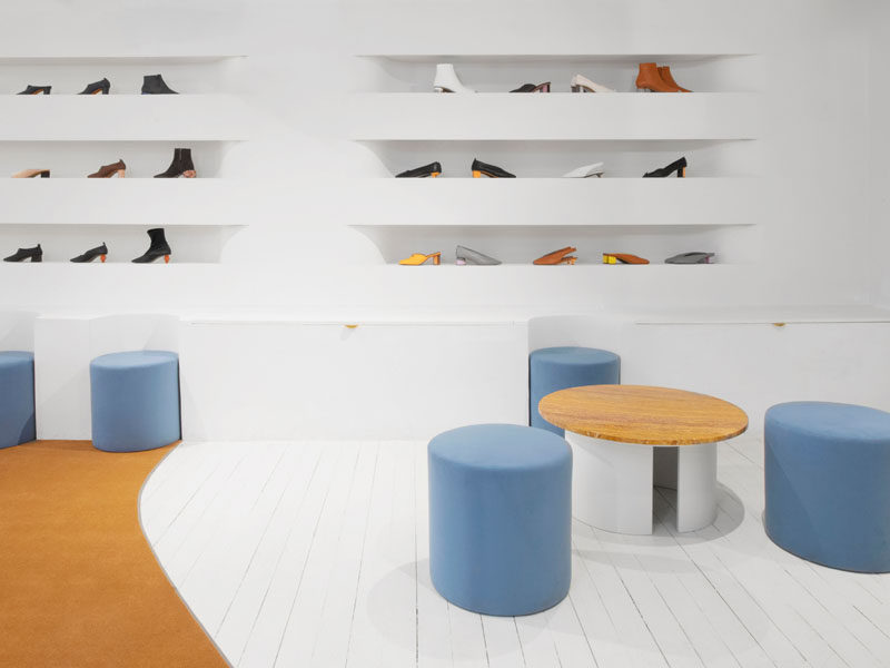 In this showroom, the seats seamlessly fit in with the white benches, which also offer additional room for storage, while above, the soft, curved lines of the shelving tuck into the wall to create a visual pattern of smoothed rectangles. #Showroom #InteriorDesign