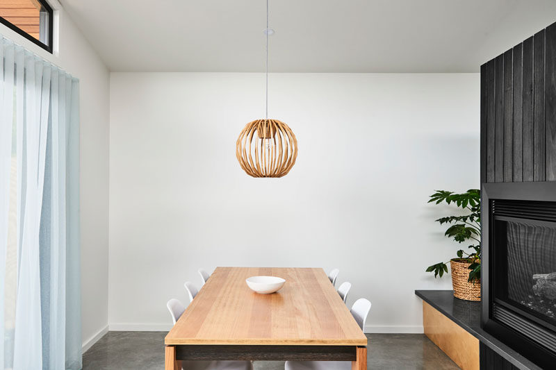 In this minimalist dining room, a single wood pendant light hangs above the dining table that's surrounded by white chairs. #DiningRoom