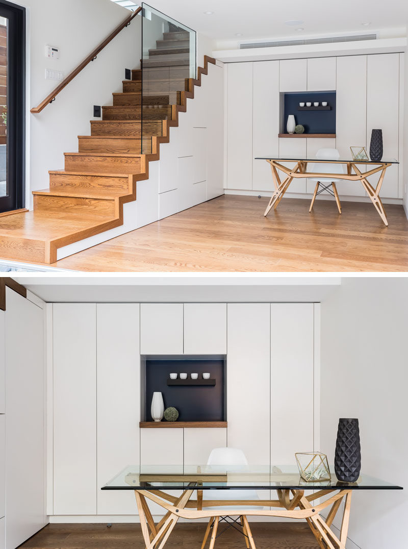 This modern bonus room has been set up as a home office, with floor-to-ceiling minimalist white cabinets and a hidden powder room under the stairs. #BonusRoom #HomeOffice #Stairs #WhiteCabinets