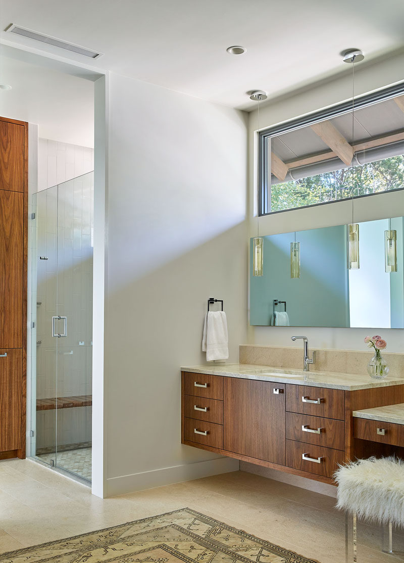 In this master bathroom, light colored walls and floors have been combined with  wood cabinetry for a contemporary appearance. #Bathroom #MasterBathroom