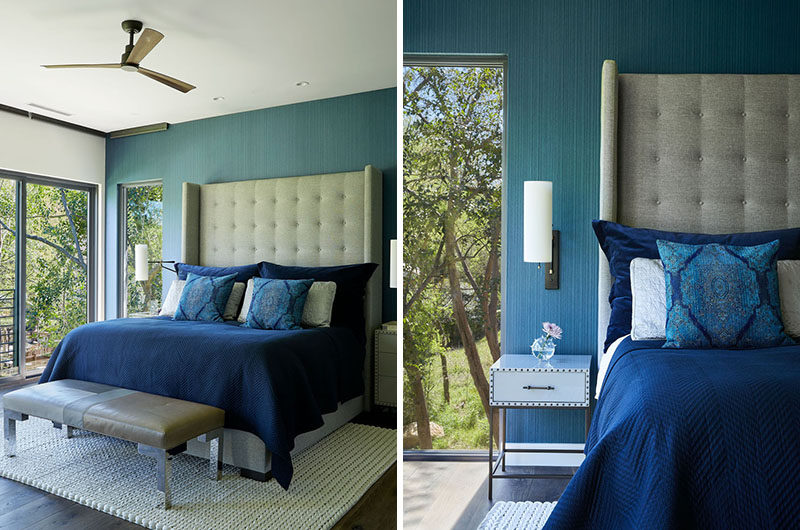 In this master bedroom, a blue accent wall creates a colorful backdrop for the bed, while the windows provide tree views. #MasterBedroom #BlueBedroom