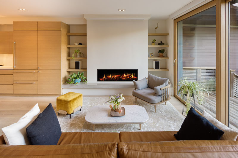 This living room is focused on the fireplace that has built-in shelving on either side. A large 3-panel lift and slide glass door opens the living room to the backyard. #LivingRoom #Fireplace #Shelving