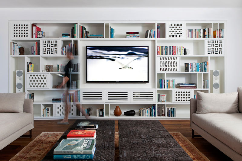 This modern apartment has a custom-designed shelving unit in the living room, that's filled with playful patterns and plenty of storage. #Shelving #LivingRoom #Library #Bookshelf