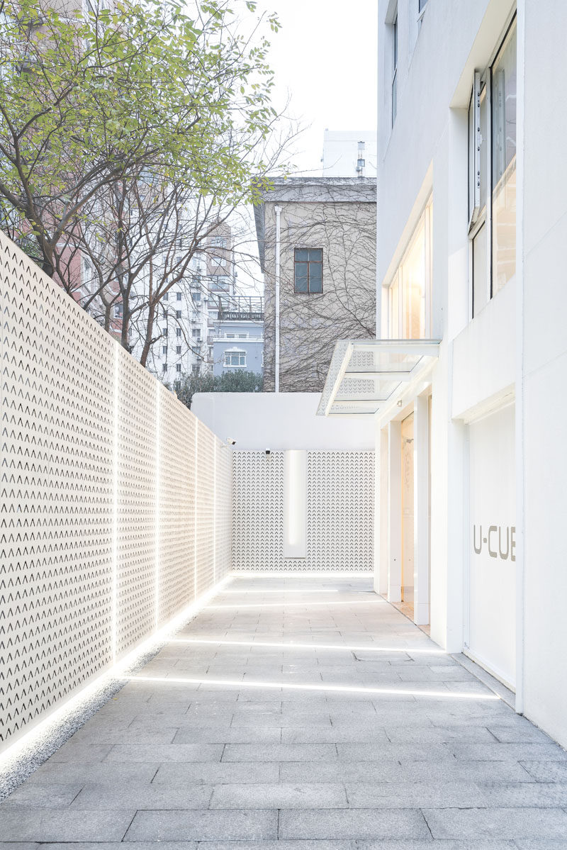 To brighten up an alleyway, lighting runs from the building, across the ground, and up onto a decorative fence. #Lighting #BuildingDesign