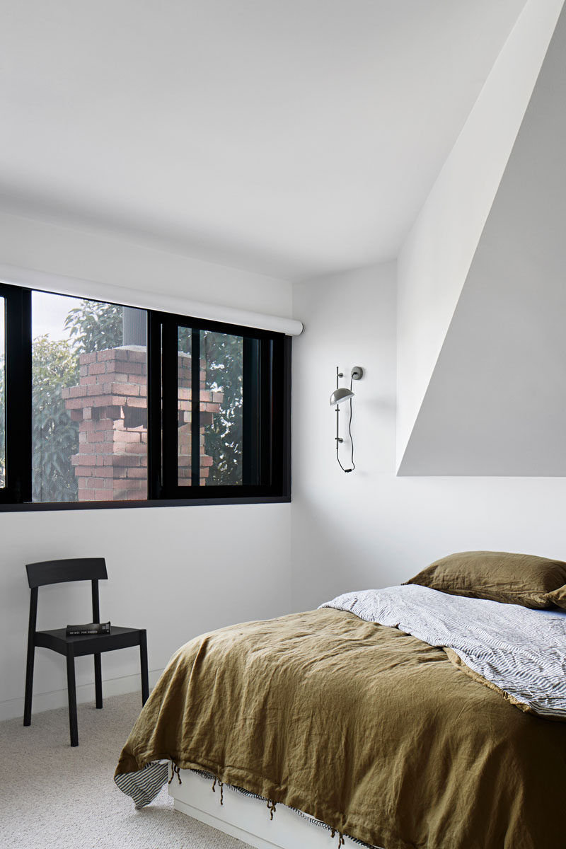 In this modern bedroom, white walls and high ceilings gives the room a lofty feeling, while the windows provide tree views and a glimpse of a brick chimney. #ModernBedroom