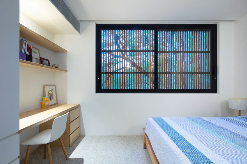 In this modern bedroom, the movable timber batten screens on the exterior of the house provide privacy when closed, while a built-in desk and open shelving have been added between the closet and wall. #Bedroom #Window #Desk